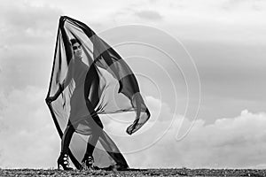 Woman in black overalls dancing with flying fabric