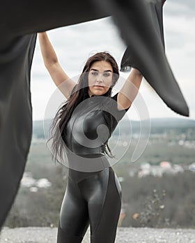 Woman in black overalls dancing with flying fabric