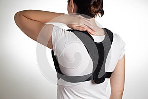 Woman in black posture corrector and fixation brace for the thoracic spine, close-up. Treatment of chronic back pain,