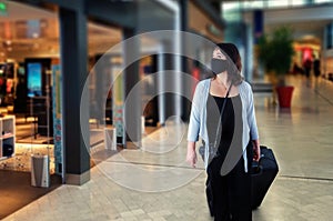Woman in black protective mask stares at the storefronts in an airport