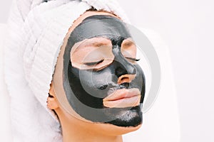 Woman with black purifying charcoal facial mask in spa. Cosmetology and skincare. Beauty treatments. Spa therapy.