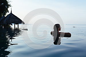 Woman black silhouette at infinity swimming pool