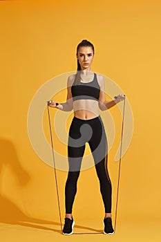 Woman in black sportswear with jumping rope