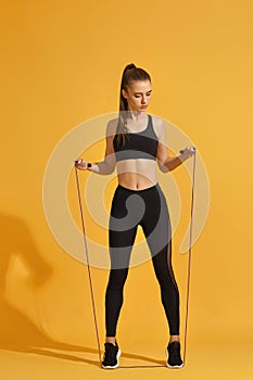 Woman in black sportswear with jumping rope