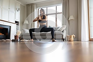 Woman in black sportswear practicing yoga, do Sumo Squat pose