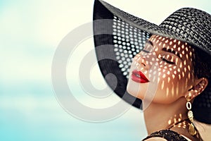 Woman in Black Summer Hat with Red Lips Make up. Fashion Luxury Model wearing Sun Hat with Shadows on Face. Women Beauty Portrait