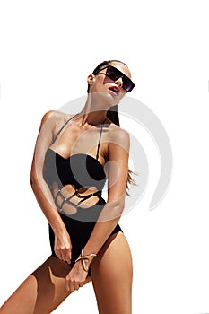 Woman in black sunglasses and swimsuit wearing golden bracelet with hair up poses on isolated white background. Fashion