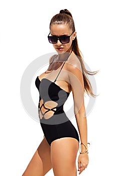 Woman in black sunglasses and swimsuit wearing golden bracelet with hair up poses on isolated white background. Fashion