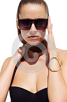 Woman in black sunglasses and swimsuit wearing golden bracelet with hair up poses on isolated white background. Fashion