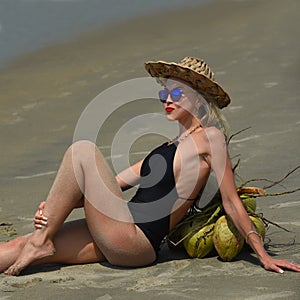 Woman in a black swimsuit and hat relaxing on the tropical beach