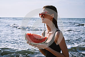 woman in black swimsuit with watermelon by the ocean