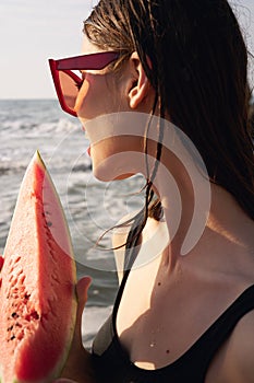 woman in black swimsuit with watermelon by the ocean