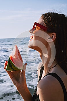 woman in black swimsuit with watermelon by the ocean