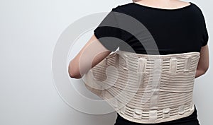 Woman in black t-shirt wearing back support belt for back pain and spinal support. Medical care concept