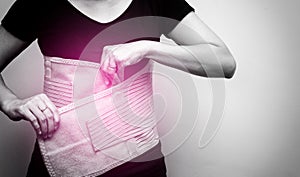 Woman in black t-shirt wearing back support belt for back pain and spinal support. Medical care concept