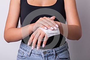 Woman in black tank top with light pink nails cleaning hands with wet wipes - hygiene procedure and prevention of infectious