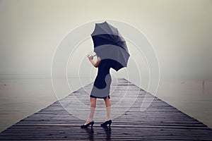 Woman with black umbrella looking infinity in a surreal place