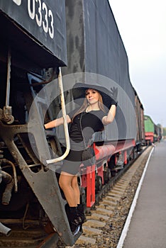 A woman in a black vintage dress on the old locomotive