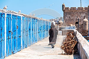 Woman in black walking in a city and port on the Atlantic coast Essaouira, Morocco