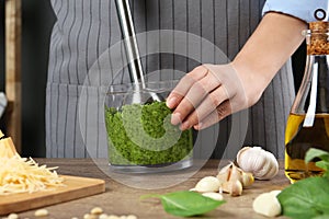 Woman blending pesto sauce in bowl at table