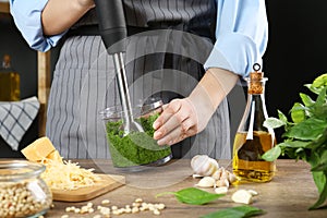 Woman blending pesto sauce in bowl at table