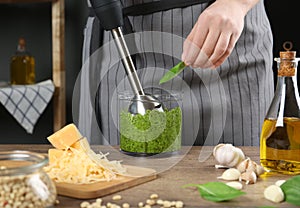 Woman blending pesto sauce in bowl at table