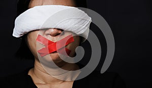 Woman blindfold wrapping mouth with red adhesive tape, tied with chains and closed her eyes