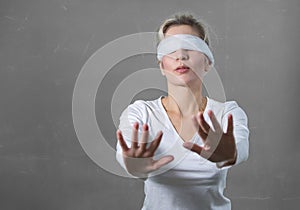 Woman blindfolded with hands reaching forward photo