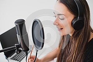 Woman blogger recording radio podcast in studio.