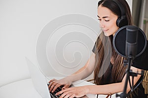 Woman blogger recording radio podcast in studio.