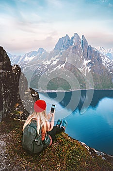 Woman blogger taking photo by smartphone of mountains and fjord landscape in Norway tourist girl traveling hiking with backpack