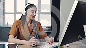 Woman blogger or vlogger streaming online on social media to her subscribers. Woman using microphone and computer for