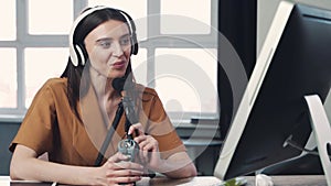 Woman blogger or vlogger streaming online on social media to her subscribers. Woman using microphone and computer for
