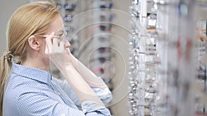 Woman blond girl is choosing new eyeglasses in optics
