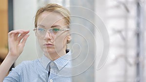 Woman blond girl is choosing new eyeglasses in optics