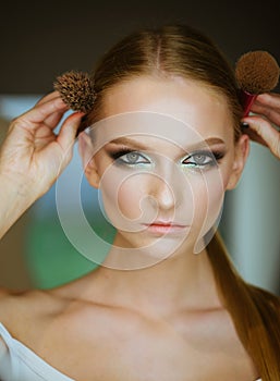 Woman with blond hair and makeup brushes, beauty. Woman with makeup face hold brushes at head. Girl with young skin face