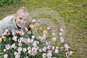 woman with blond hair near a flower bed. Portrait of a smiling girl