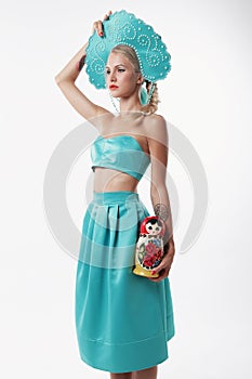 Woman with blond hair in russian national hat holding matrioshka doll