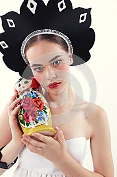 Woman with blond hair in russian national hat holding matrioshka doll