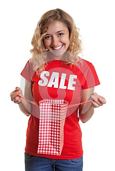 Woman with blond hair in a sales-shirt holding a shopping bag