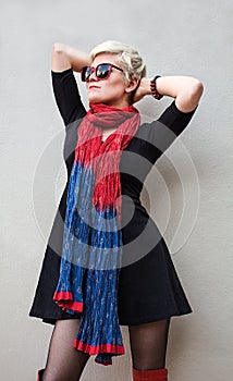Woman blonde in black little dress, red scarf, sunglasses. Fashion model shot.