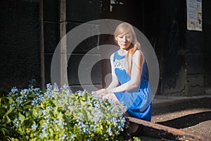 Woman blonde in blue dress walking along a city street against a background of urban architecture and summer Siberian beauties