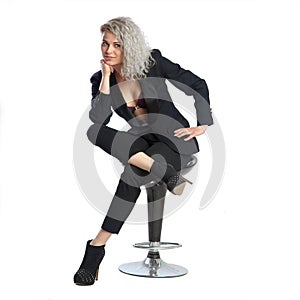 woman with blonde curly hair in black business suit sits on chair