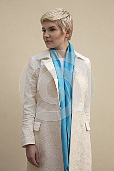 Woman blonde in white coat, blue scarf. Fashion hairstyle.