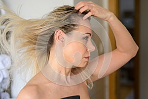 Woman blow drying her lotrng blond hair