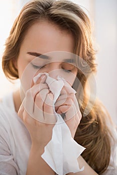 Woman blowing her nose on couch