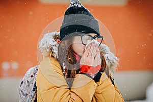 Woman blowing her nose into handkerchief. Young woman getting sick with flu in a winter day