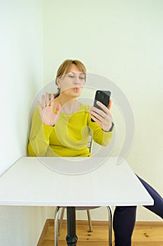 Woman blowing a kiss in smartphone communicates in online chat and social networks with her close people sitting at home on white