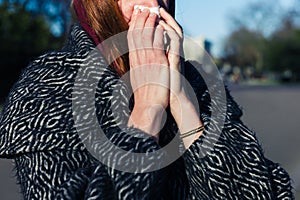 Woman blowing nose in park