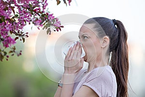 Woman blowing nose because of spring pollen allergy